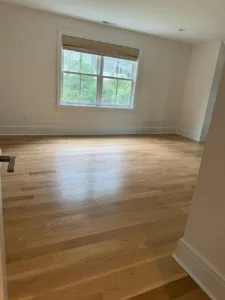 Freshly installed hardwood floor in a spacious room with natural light, highlighting the clean finish.