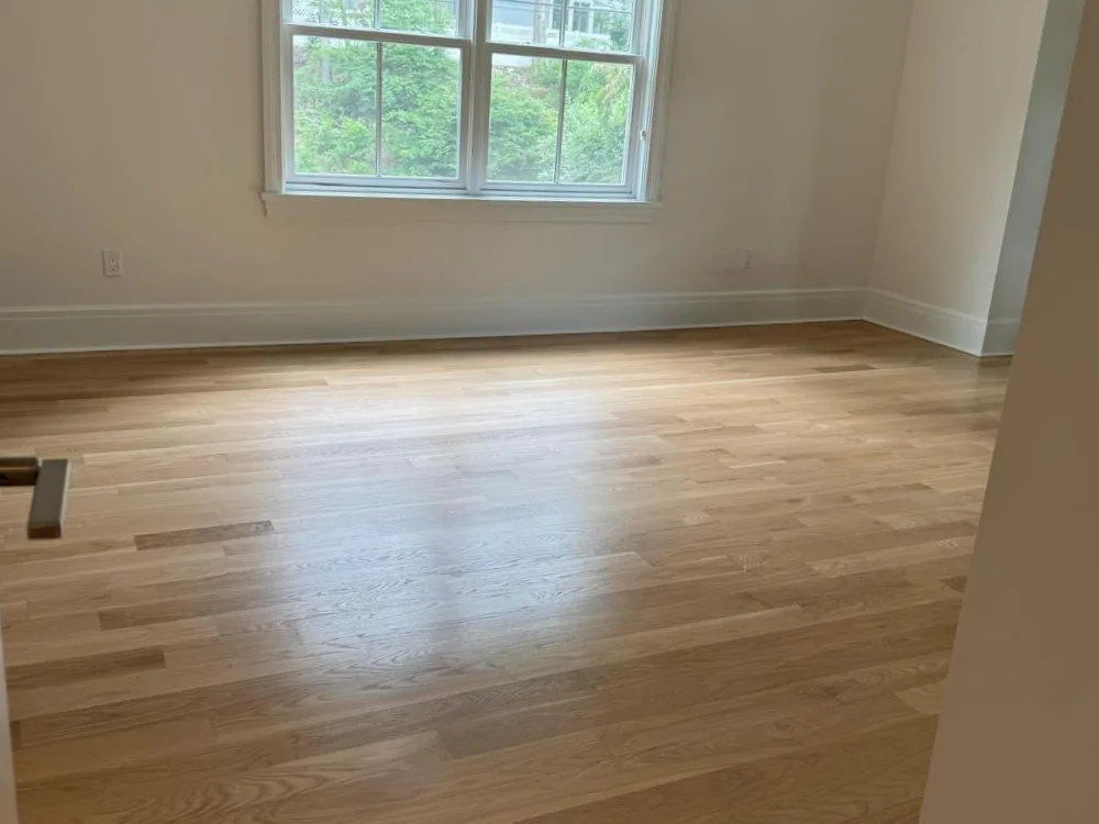 Wooden flooring installation in a newly renovated room, showing smooth hardwood planks.