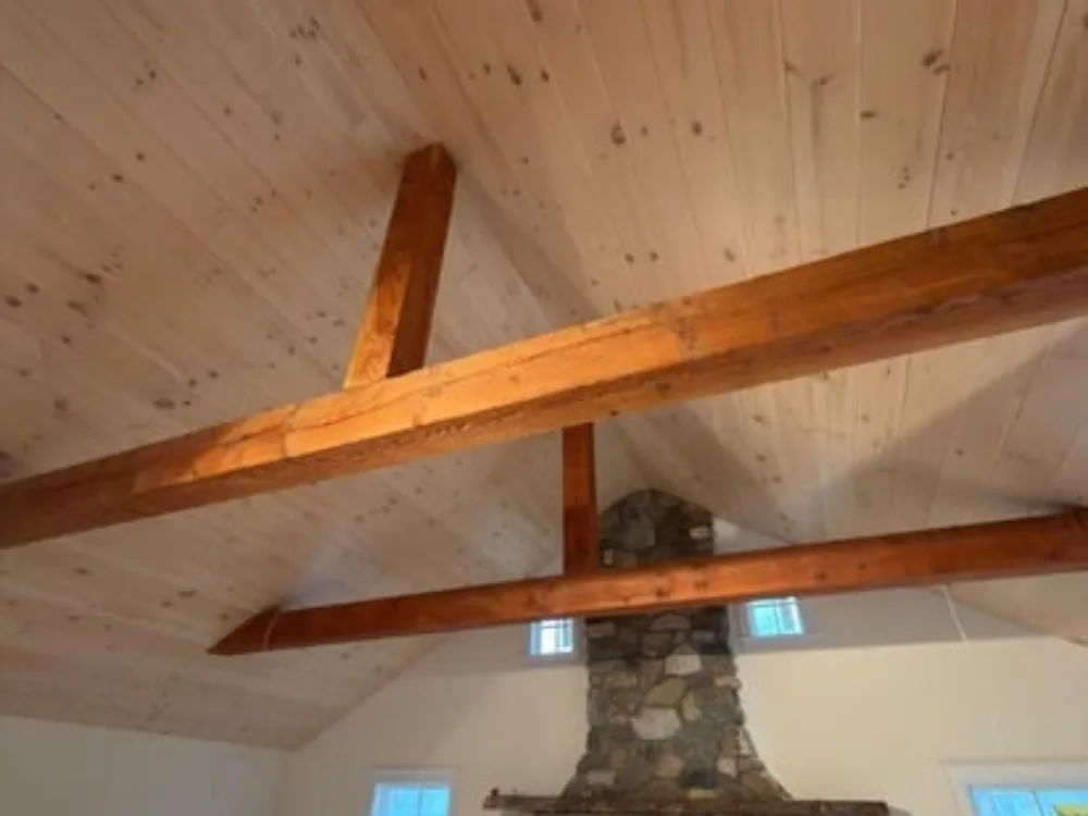 Looking up at the vaulted Eastern White Pine Ceiling intersecting with large exposed wooden beams.