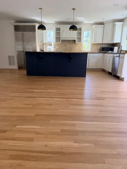 A centered view of the kitchen space highlighting the contrast between the dark island and Fairfield custom stained floors.