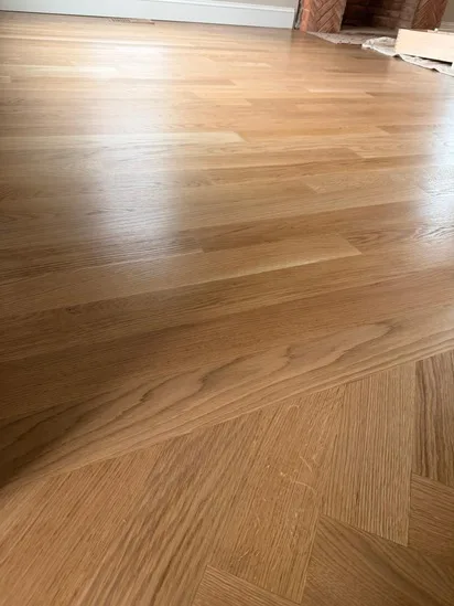 Detailed close-up view of refinished weathered oak hardwood flooring meeting a decorative herringbone border pattern, highlighting the precise transitions in this weathered oak flooring refinishing project.